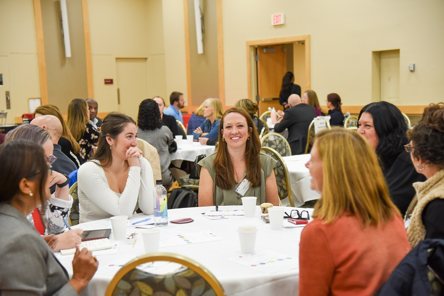 women sitting around a table talking and laughing at a conference