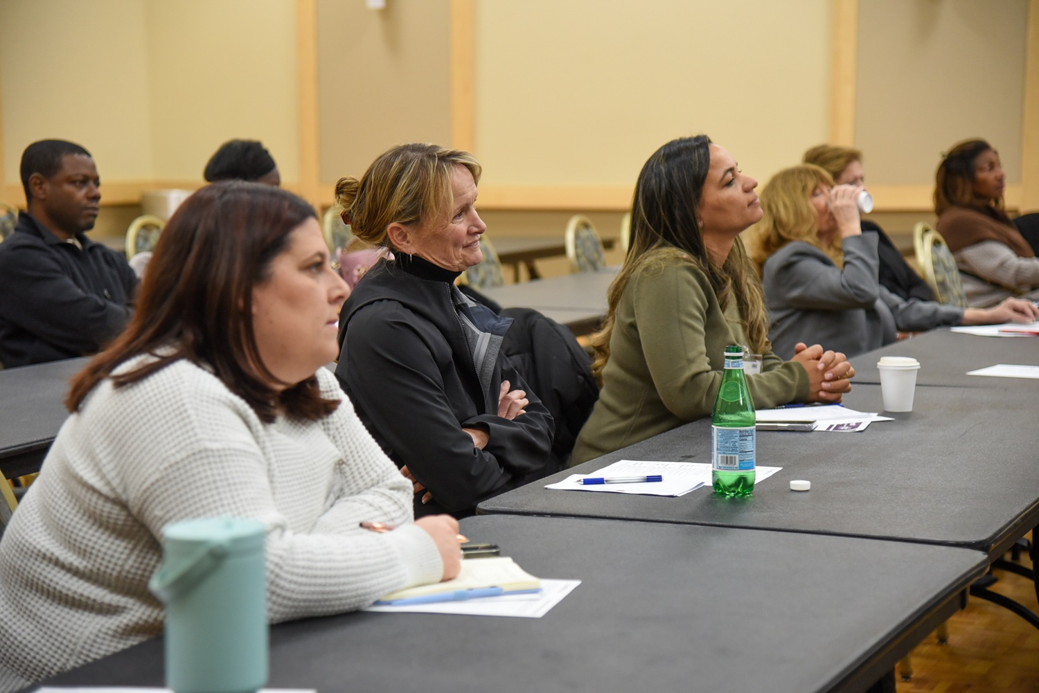 men and women at classroom tables listening