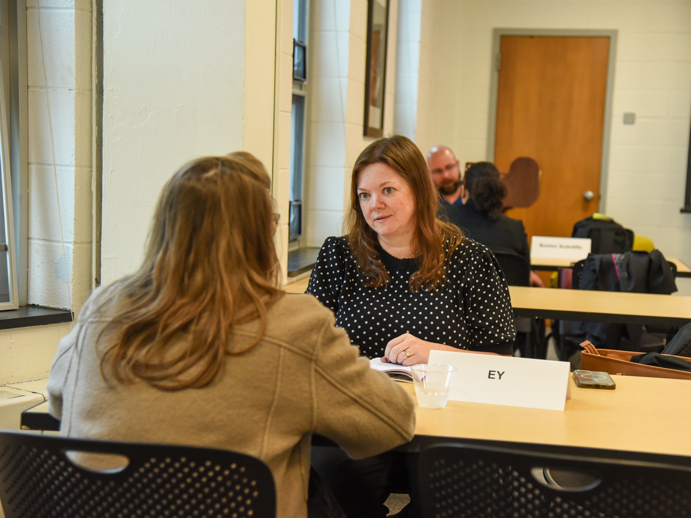 Two women at table talking to eachother