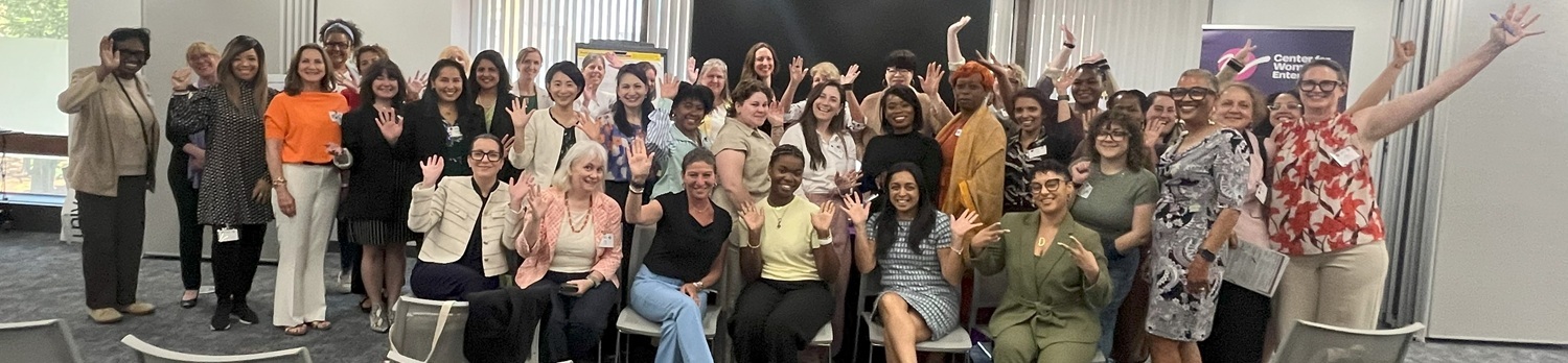 large group of women waving at a conference