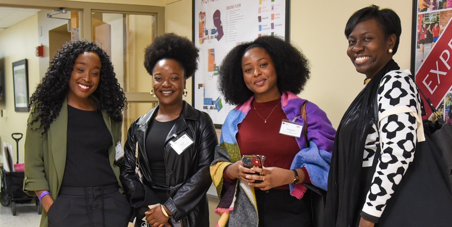 4 women in hallway smiling at camera