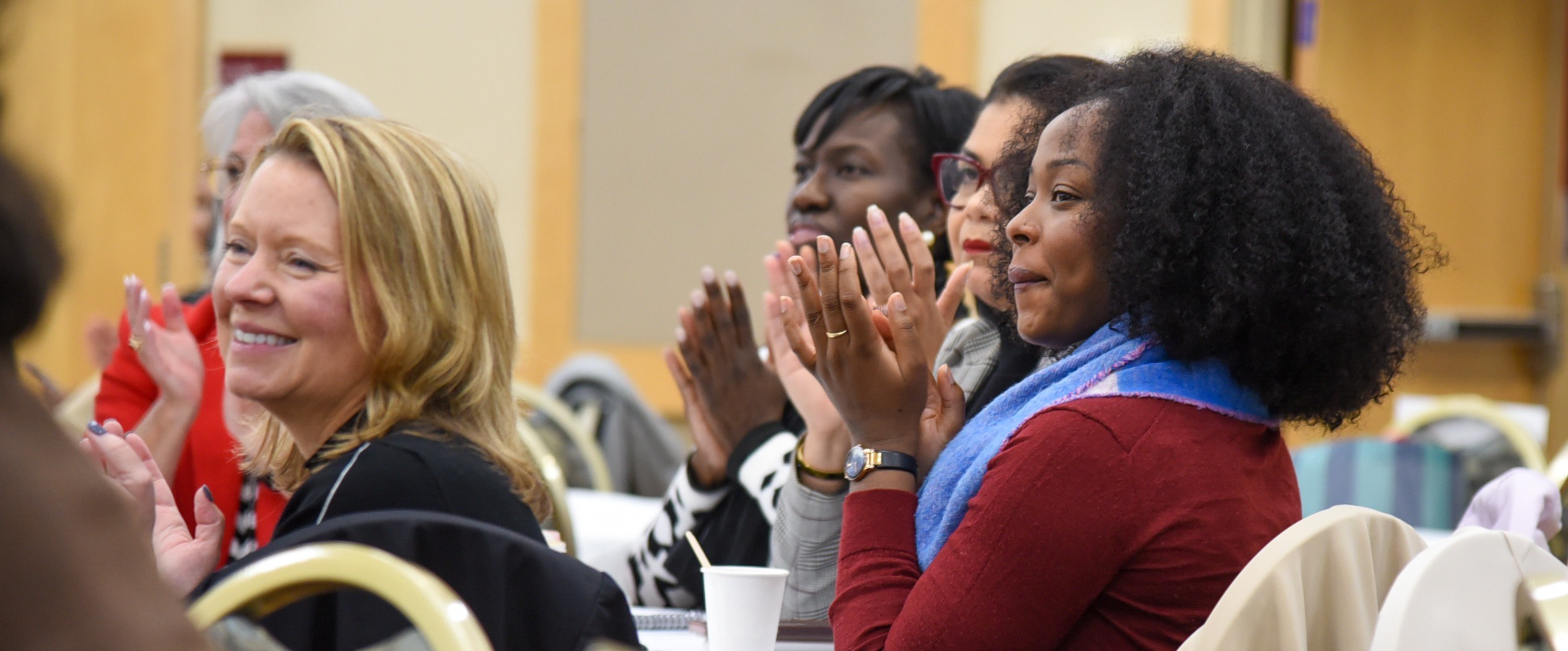 5 women clapping and looking forward while seated