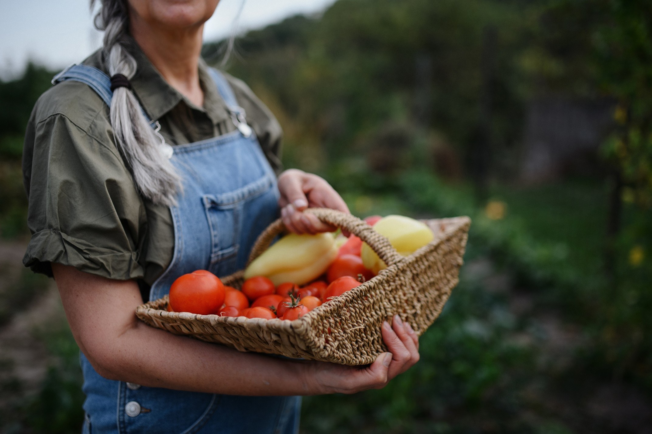 women in coveralls with basket of produce